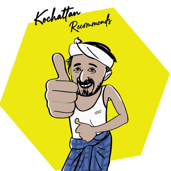 Kochattan, our friendly village guide, giving a thumbs-up. He wears a white thorthu on his head and a blue checked lungi.